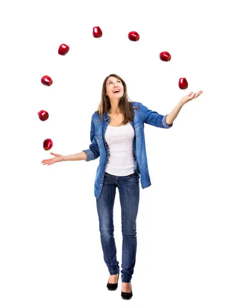 Healthy woman throwing apples, isolated over a white background