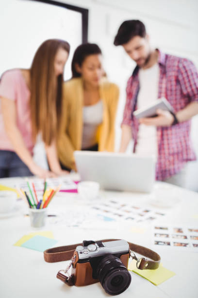 istock Close-up of camera on desk with editors working at creative office 649457438