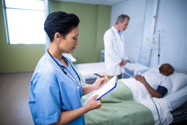 istock Female nurse writing on clipboard during visit in ward 649497434
