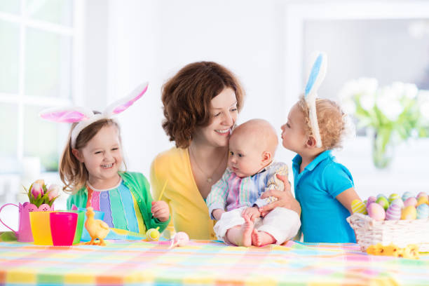 istock Mother with three children painting Easter eggs 649510676