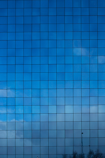 Glass building façade with reflection of the sky above it.