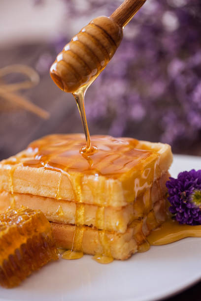 istock dripping honey from a wooden dipper on waffle 649511402