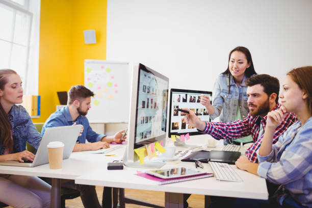 istock Businessman showing computer screen to coworkers 649511464