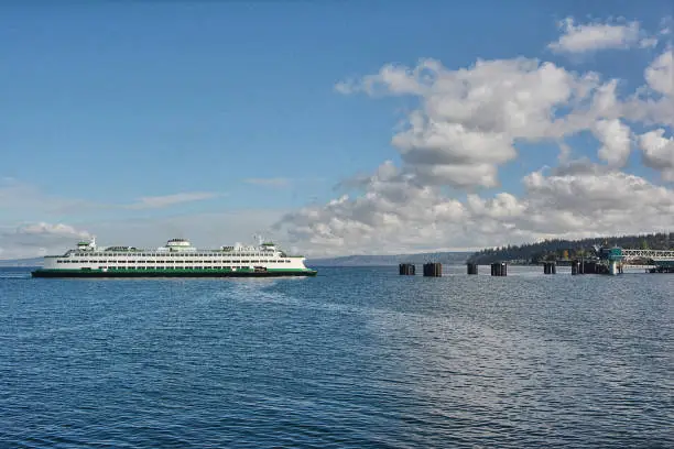A dramatic sky background with a  Puget Sound ferry arriving at a dock.