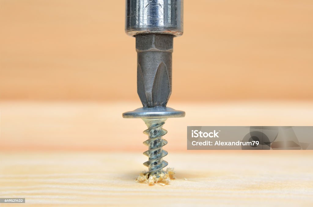 Screws screwdriver twist in wooden board. Screws screwdriver twist in wooden board. Joinery and construction work close up. Power tool operation. Screw Stock Photo