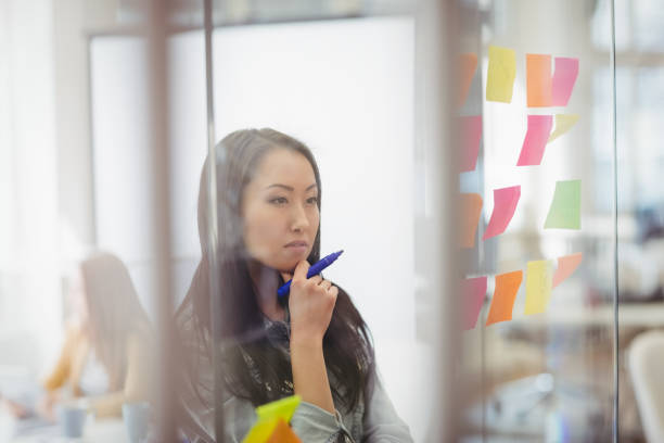 istock Thoughtful photo editor looking at multi colored sticky notes on glass 649525144