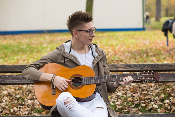 istock Man playing a guitar in nature 649528106