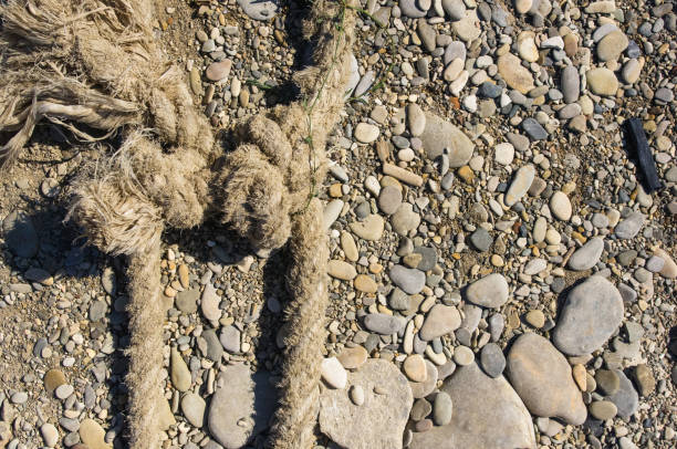 old worn battered marine rope on the pebble beach on a Sunny summer day, top view