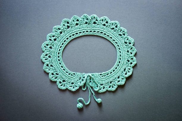 Crocheted green fashion collar laid flat on a gray background
