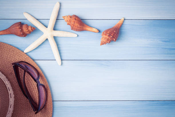 istock Starfish hat and shells on blue wooden floor 649576930