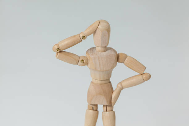 istock Confused wooden figurine standing with hand on head 649583496