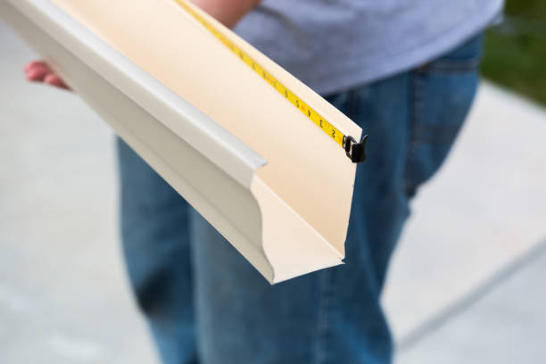 Worker Measuring Rain Gutter Processing Through Seamless Shaping Machine stock photo