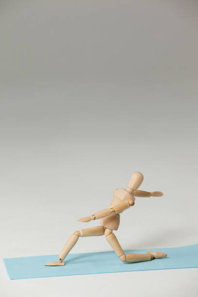 Wooden figurine exercising on exercise mat against white background