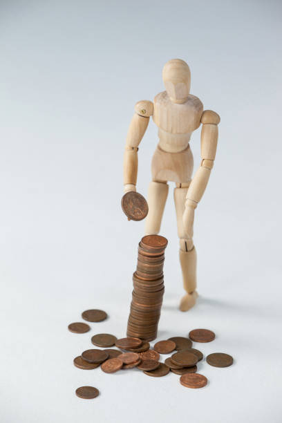 istock Wooden figurine standing and making stack of coins 649587408