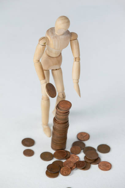 istock Wooden figurine standing and making stack of coins 649587416