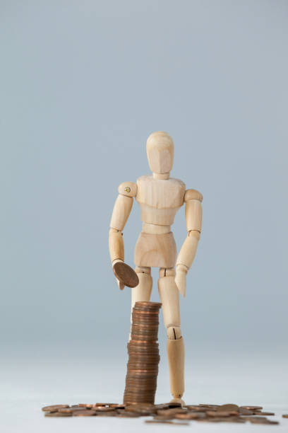 istock Wooden figurine standing and making stack of coins 649587448