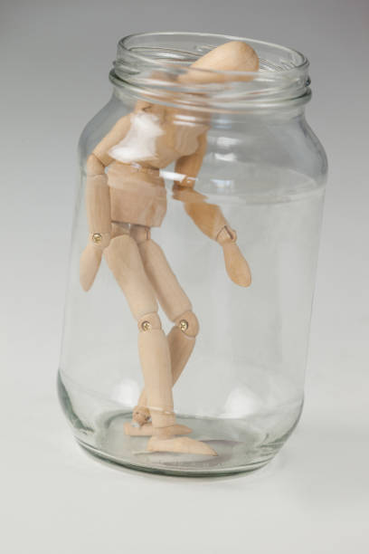 istock Wooden figurine standing inside a glass jar 649587464