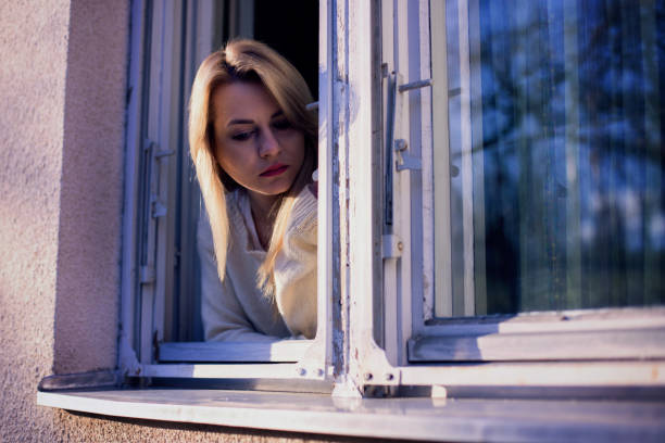 istock Blonde woman leaning on window at morning 649594452