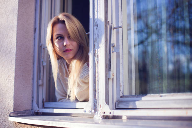 istock Blonde woman leaning on window at morning 649594582