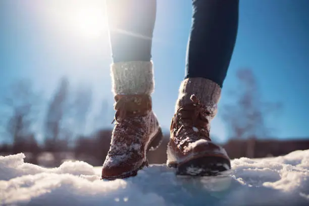 Close-up of a female mountaineer legs walking through snow.