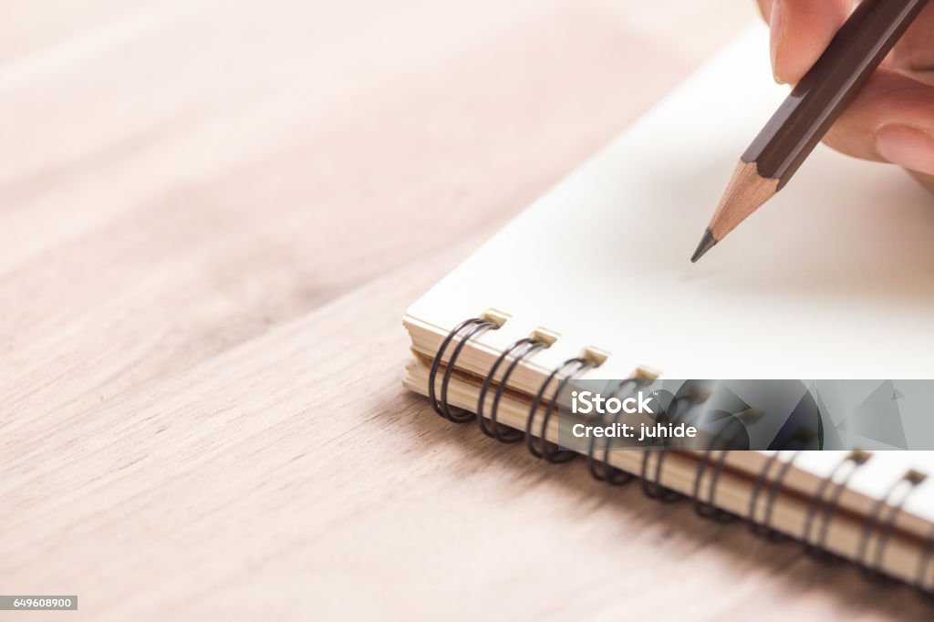 Hands writing on notebook Business women hands working writing on notebook on wooden desk, lighting effect Note Pad Stock Photo