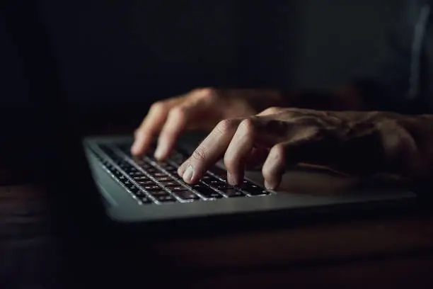 High angle shot of an unidentifiable man using a laptop late at night