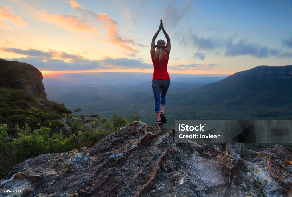 Female fitness stretch to the sky mountain top valley scene Arms outstretched,  reach for the sky. Stand on tippy toes, oh,oh,so high.  Woman on the edge of a mountain cliff with valley views stretches her arms toward the sky. Blue Mountains - Australia Stock Photo