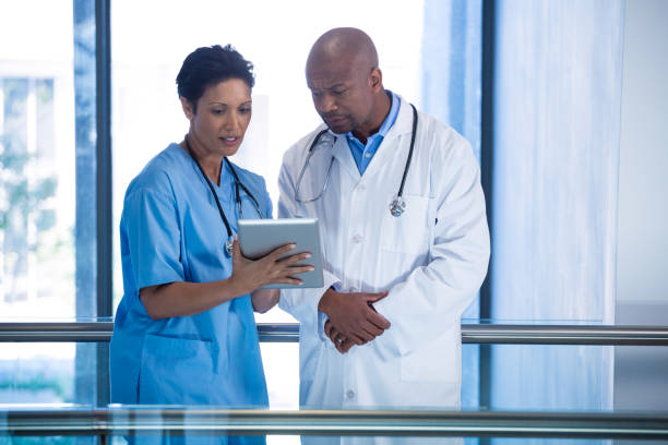 istock Male doctor and nurse using digital tablet in corridor 649625310
