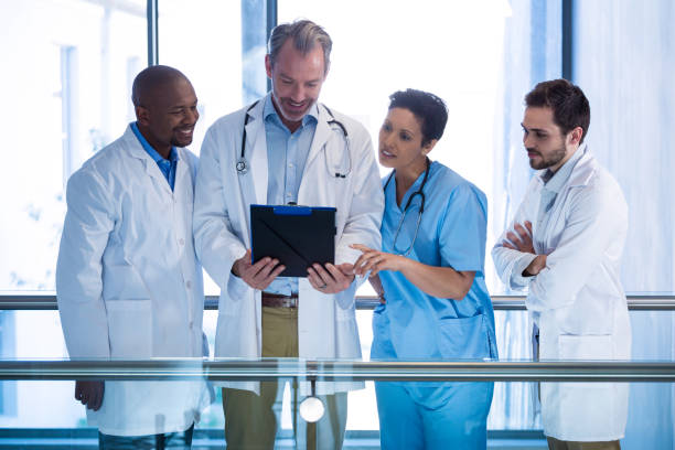 istock Male doctors and nurse having discussion over clipboard in corridor 649625436