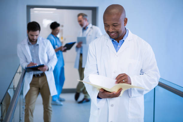 istock Male doctor reading reports in corridor 649625510
