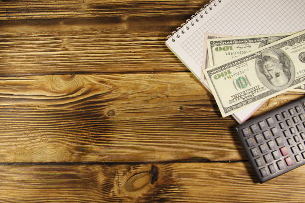 istock Notebook with dollars and calculator on wooden desk 649633028