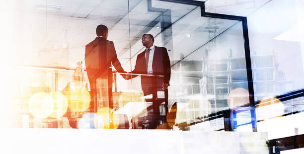We'll do great things together Shot of two businessmen shaking hands superimposed over a cityscape hello stock pictures, royalty-free photos & images