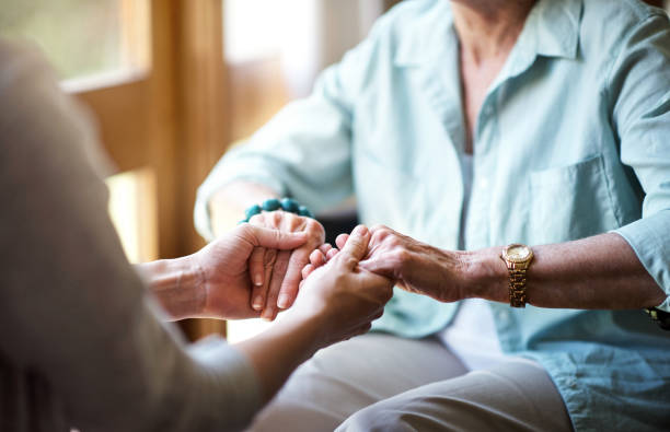 tendre la main dans le confort et soutien - human hand old senior adult holding hands photos et images de collection