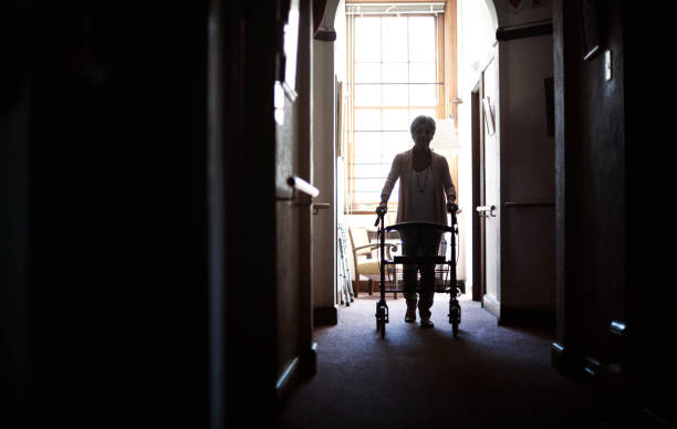 Silhouette of a senior woman using a walker in the hallway of a retirement home