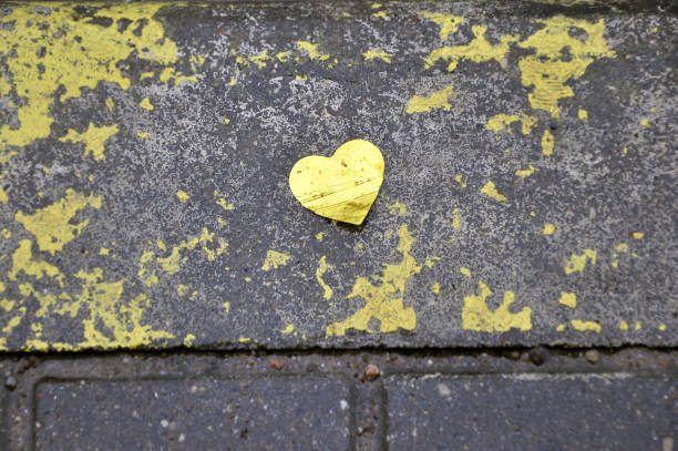 istock Yellow heart of foil on wet pavement. Background texture. 649646032