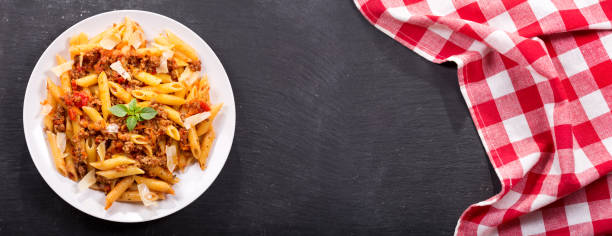 plate of pasta bolognese on dark table
