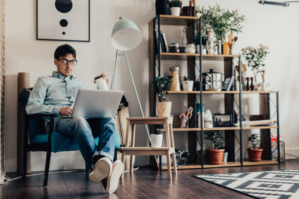 istock Young caucasian man sits at home and uses computer for surfing the net 649650096