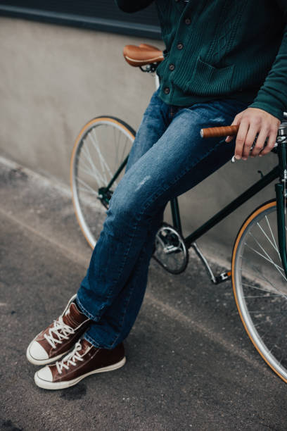 istock Man in jeans and sneakers leaning on bicycle 649654776