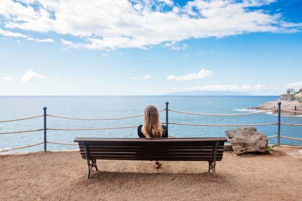 istock Alone young woman sitting on the bench 649657480