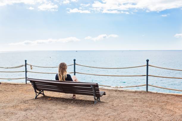istock Alone young woman sitting on the bench 649657552