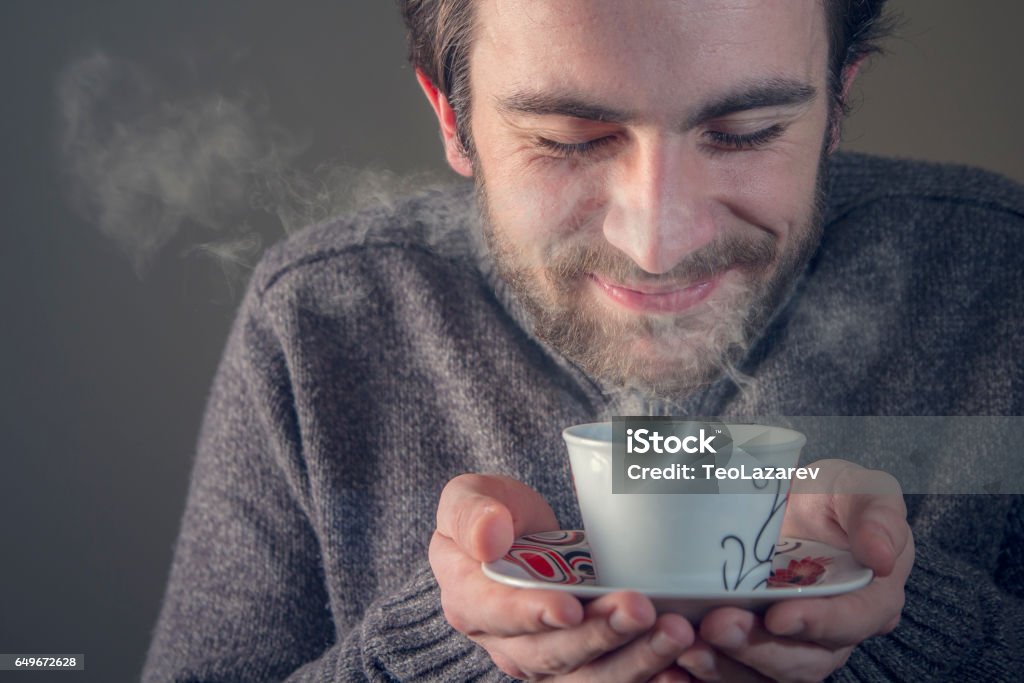 Sweet smell of a hot drink Young man enjoying the smell of his hot beverage, tea or coffee, anticipating the sweet taste Men Stock Photo