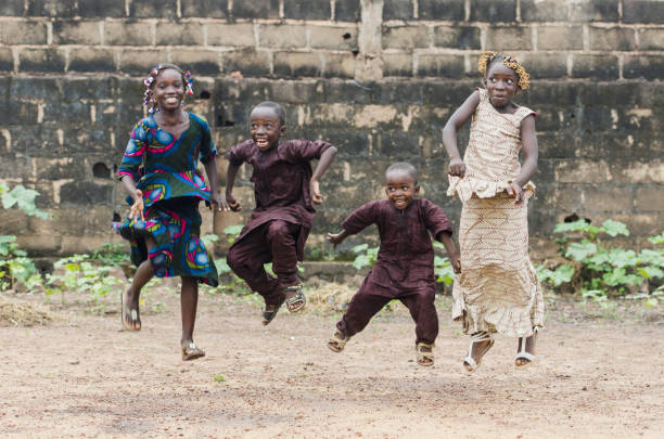 Four African children jumping as high as possible playing outdoors Little african children jumping and having fun in front of camera poverty child ethnic indigenous culture stock pictures, royalty-free photos & images