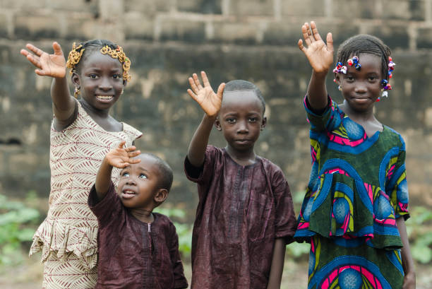 Four African children waving goodbye or saying hello! Little african children waving hands on blurred background poverty photos stock pictures, royalty-free photos & images