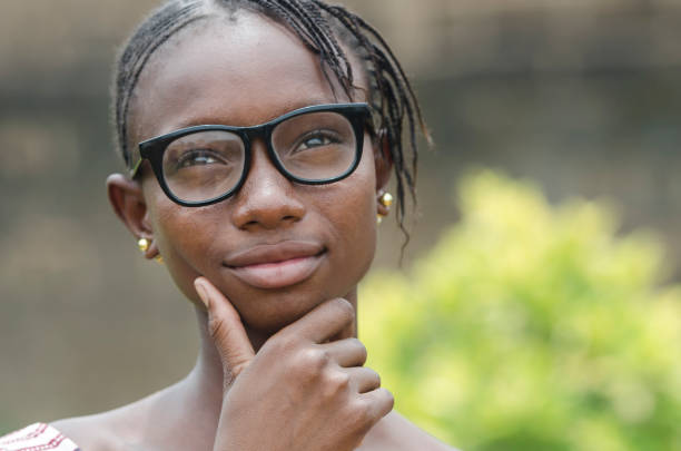 Africa's Future - Teenage Schoolgirl thinking about her future on the African continent Young african girl in eyeglasses thinking outdoors with blurred background poverty child ethnic indigenous culture stock pictures, royalty-free photos & images