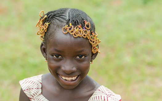 Young african girl with traditional accessories in hair looking at camera