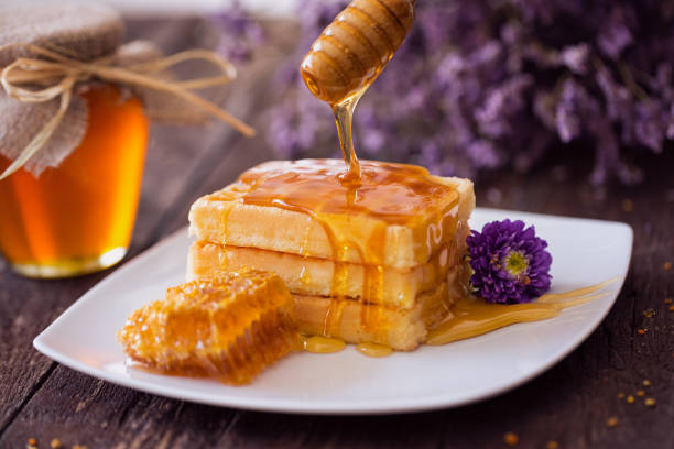 tropfende honig aus einem hölzernen wagen auf frische waffel - waffle syrup pouring breakfast stock-fotos und bilder