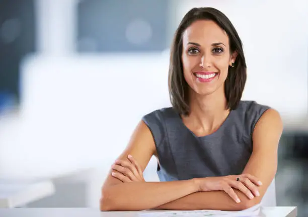 Portrait of a smiling young businesswoman sitting at a desk in an office