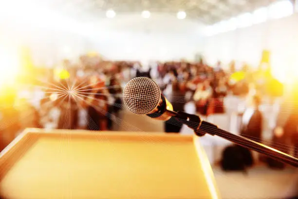 Photo of Podium with microphone infront of people seated