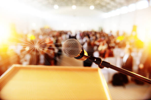 podium with microphone infront of people seated - lecture hall audio imagens e fotografias de stock