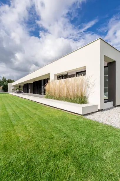 Housefront of modern villa surrounded by grass